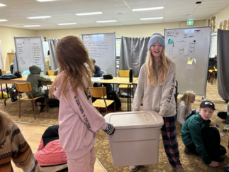 students helping with tub of stuff to move